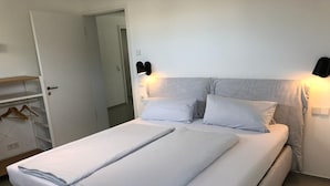A neatly made bed with two pillows, a bedside table, and a wardrobe with a mirror. - LAKE Loft Azur - in the Überlingen spa district (Überlingen)