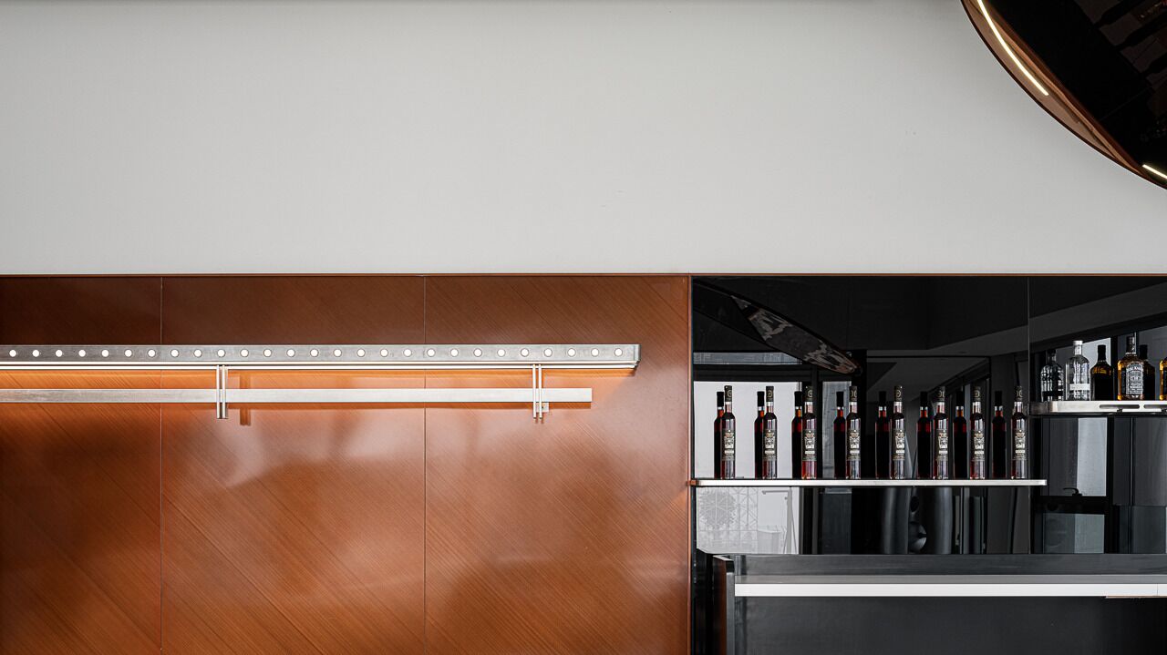 A bar area with wooden paneling and a shelf of liquor bottles.