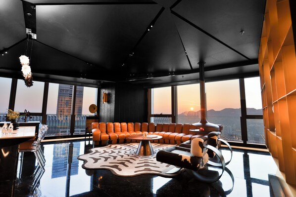 Interior moderno com teto preto, sofá de couro, mesa de centro de vidro e vista para a paisagem urbana.