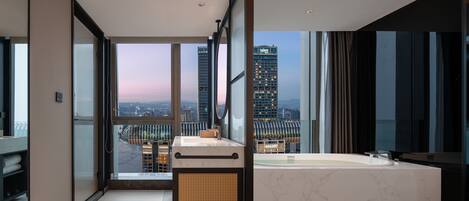 A modern bathroom with a large window, a bathtub, and a vanity with a mirror.