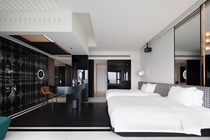 Una habitación de hotel moderna con una cama grande, un escritorio y un espejo.