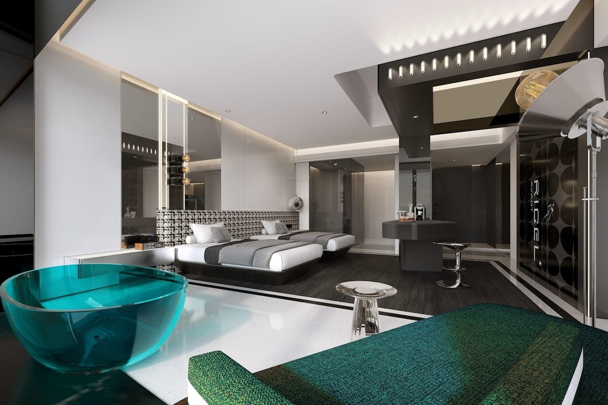 Ein modernes Hotelzimmer mit einem großen Bett, einer Glasvase auf dem Tisch und einem grünen Sofa.