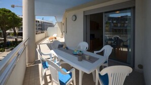 A balcony with a table and chairs, a sliding glass door, and a view of the cityscape. - Stylish house in the center of Bibione (Bibione)