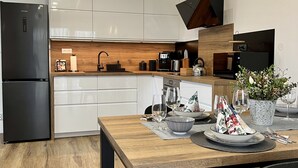Eine moderne Küche mit weißen Schränken, einem schwarzen Kühlschrank, Holz Arbeitsplatten und einem Essbereich mit Tisch für zwei Personen.