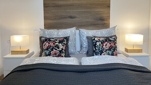 Ein Schlafzimmer mit einem Bett, zwei Nachttischen, zwei Lampen und einer Wandleuchte.