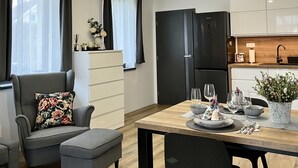 Ein modernes Wohnzimmer mit einer Couch, einem Hocker und einem Esstisch, gedeckt mit Gläsern und einer Vase.