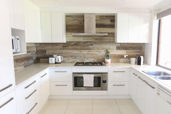 A modern kitchen with white cabinets, a built-in oven, a gas stove, and a microwave.