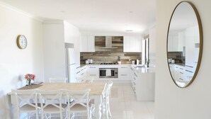 A modern kitchen with white cabinetry, a central island, and a wooden backsplash.
