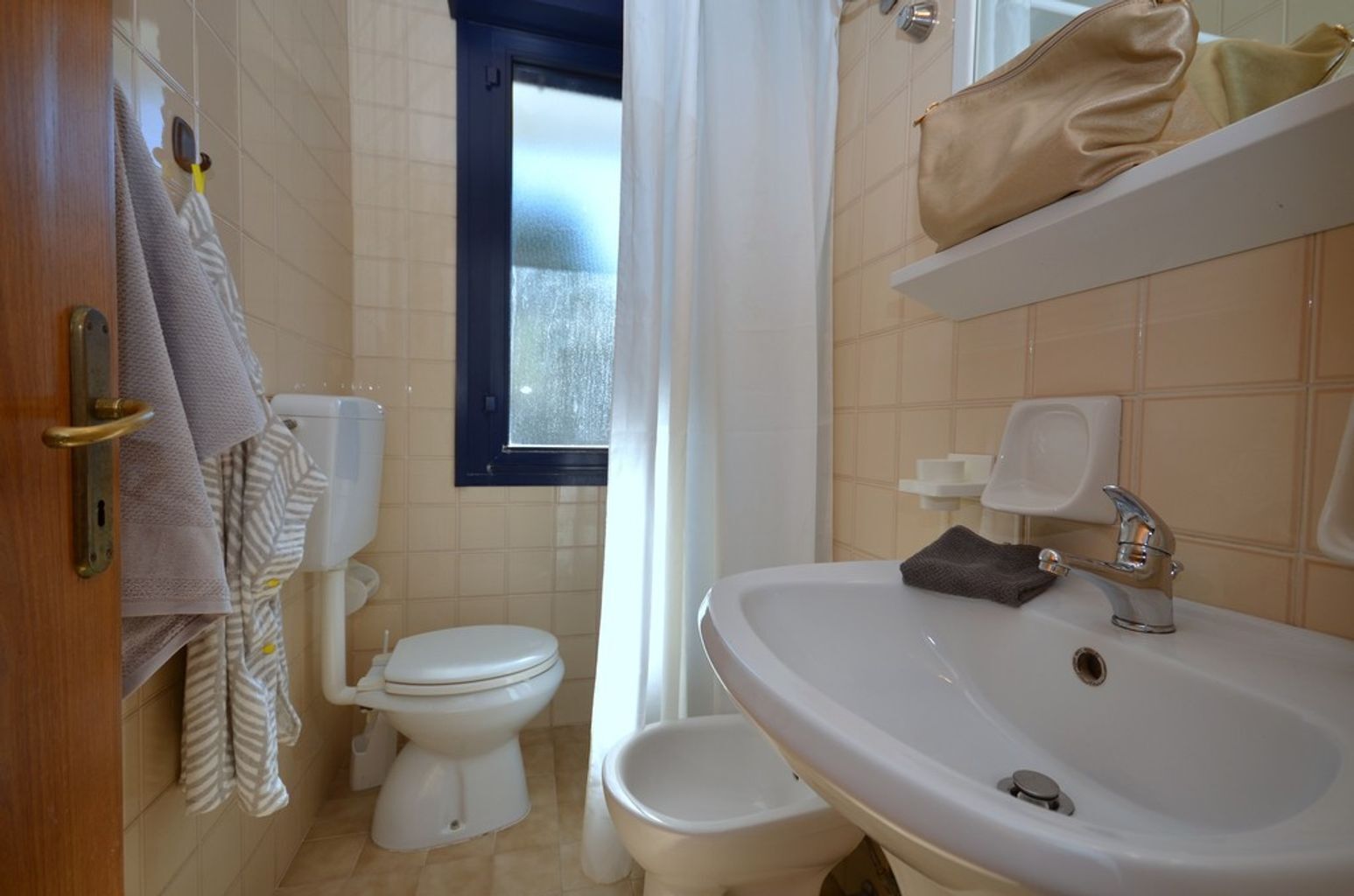 A bathroom with a toilet, bidet, sink, and a towel rack.