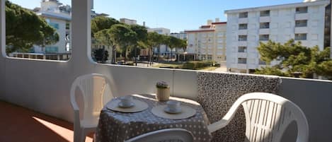 Un balcón con una mesa y sillas, con vistas a un paisaje urbano de edificios y árboles.