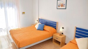 Una habitación de hotel con cama, mesita de noche y lámpara fijada a la pared.