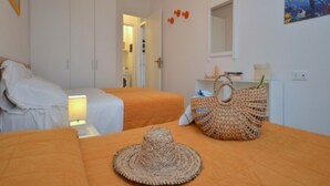 A bedroom with two beds, a woven bag, and a hat on the bed. - Contemporary renewed house (Bibione)