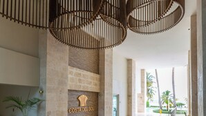 Un hall d’entrée spacieux avec un mur en pierre, un comptoir d’accueil et une enseigne indiquant « COSTA DEL SOL ».