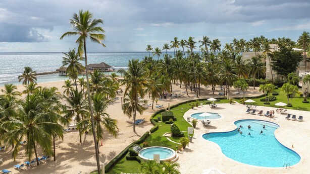 Un complexe hôtelier doté d’une grande piscine, de palmiers et d’une plage.