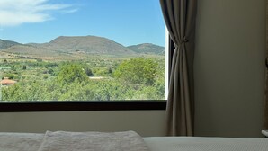 A room with a bed, a window with curtains, and a view of a mountainous landscape. - CASA YANGUAS APARTAMENTOS RURALES (Laujar de Andarax)