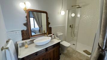 A bathroom with a large mirror, a white sink, a toilet, and a glass-enclosed shower.