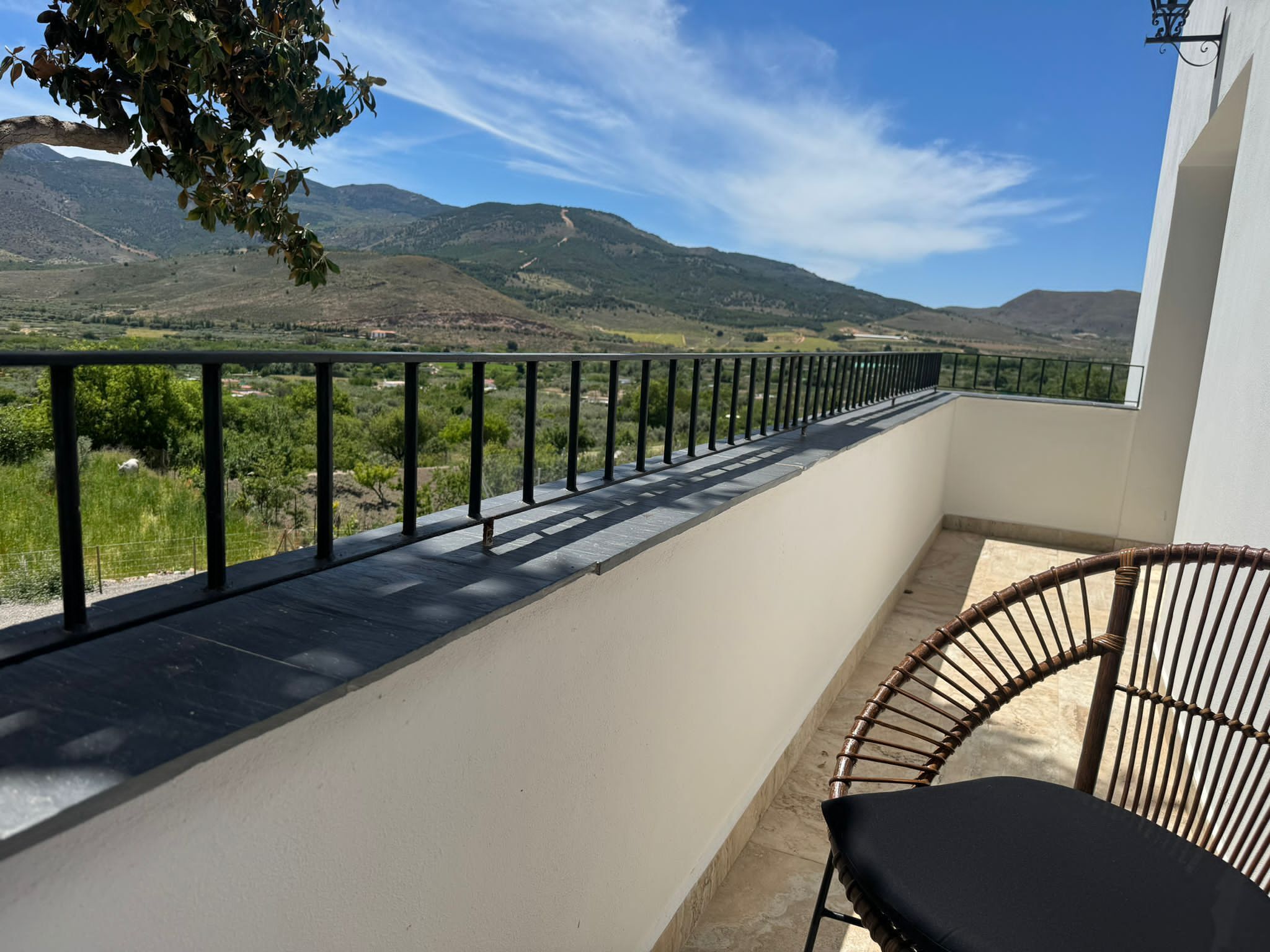 Un balcone con vista sulle montagne, una sedia e una ringhiera.