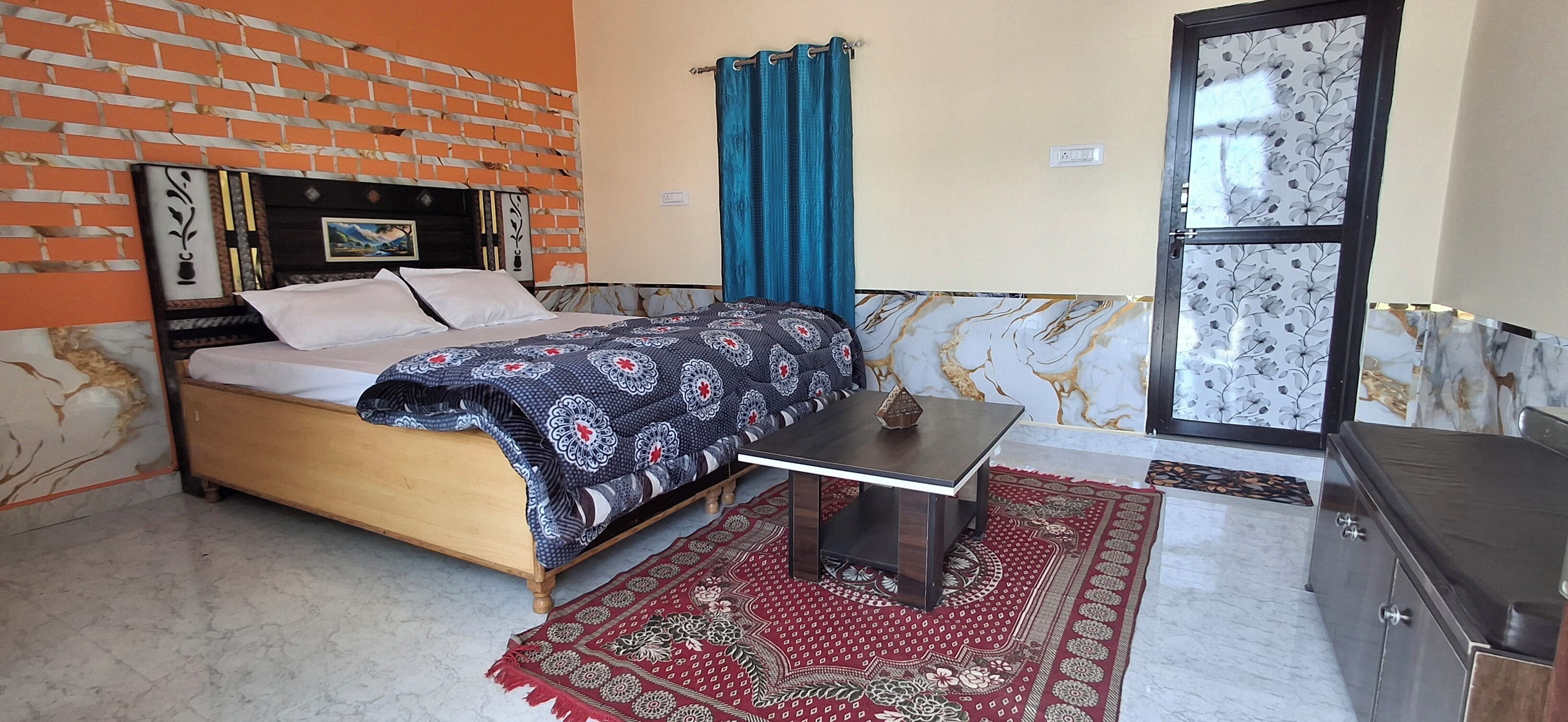 Um quarto com cama, mesa, cômoda, janela com cortinas e parede de tijolos.
