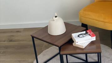 Una pequeña mesa de madera con una tetera blanca y un libro encima, sobre una alfombra redonda.