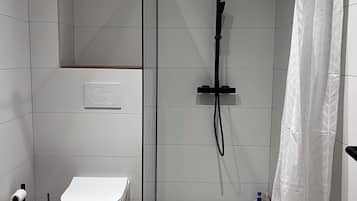 Une salle de bain moderne équipée de toilettes, d’une douche et d’un lavabo.