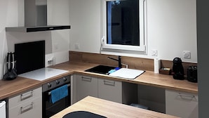 Une cuisine compacte dotée d’un four encastré, d’une plaque de cuisson et d’une fenêtre située au-dessus de l’évier.