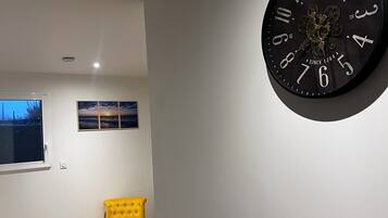 A modern living room with a large wall clock, a yellow armchair, and a wooden floor.