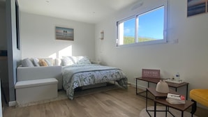 Une chambre à coucher avec un lit, un canapé, une petite table et une fenêtre.