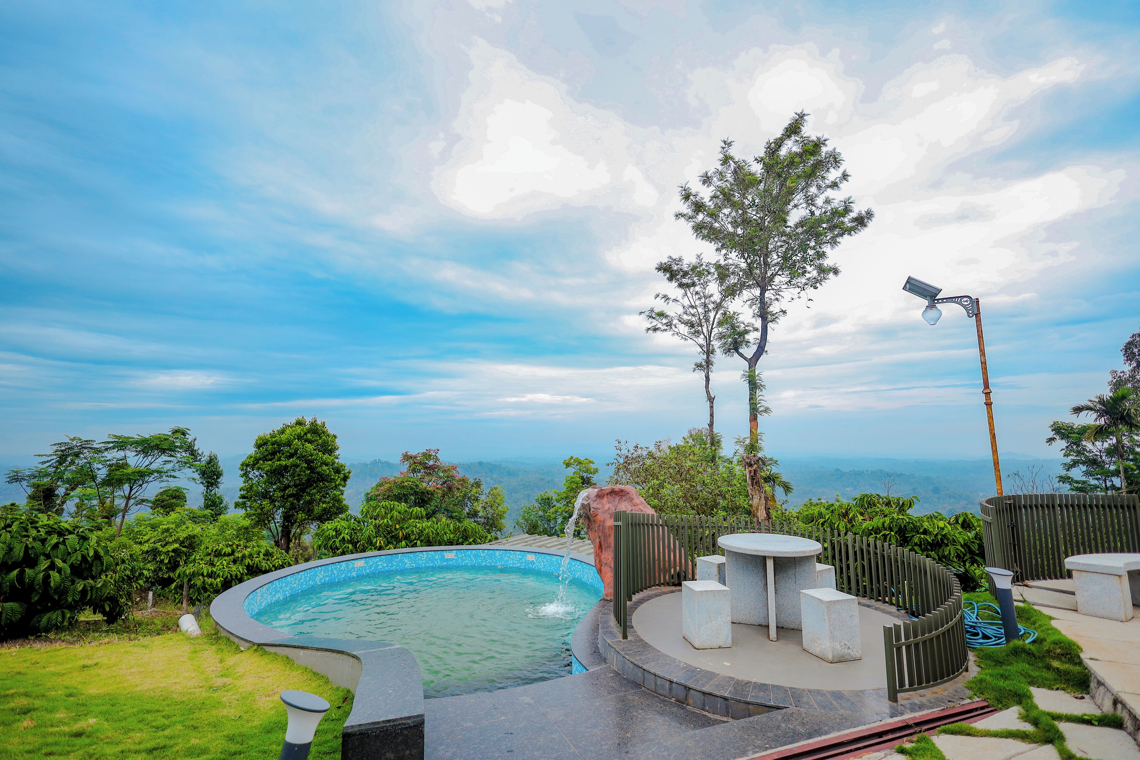 A swimming pool with a waterfall feature, surrounded by a wooden fence and seating area.
