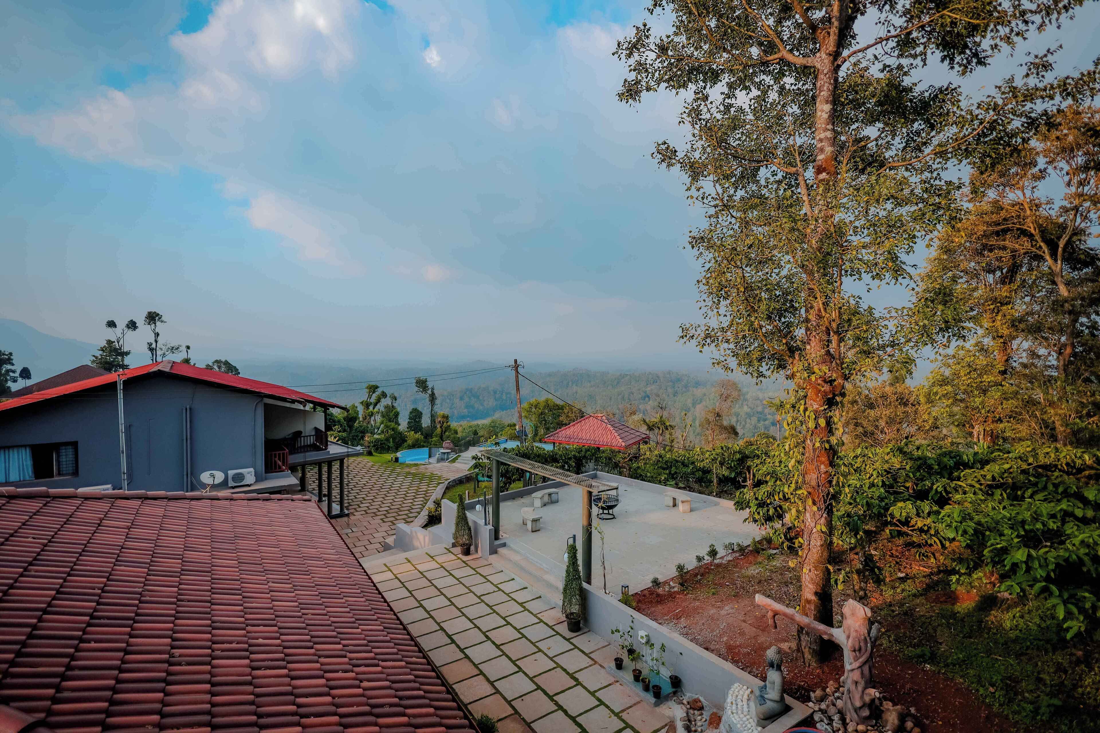 A residential area with a house featuring a red-tiled roof, a balcony, and a view of the surrounding landscape.