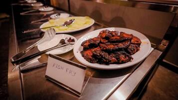 A buffet table with a sign labeled "FISH FRY" and plates of food, including fish and potatoes.