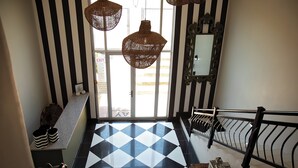 A staircase with a black and white checkered floor, a black and white striped wall, and a decorative mirror. - Stay (Tsantsabane)
