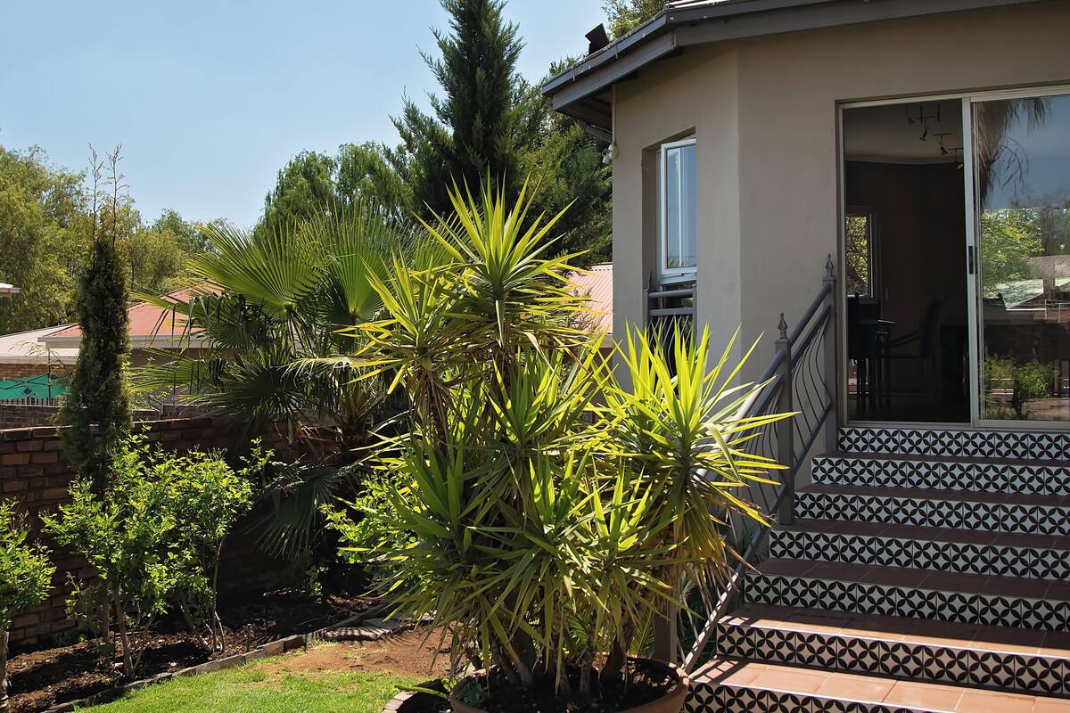 Ein Haus mit Terrasse, einem Blumentopf und einer Treppe, die zu einer Tür führt.