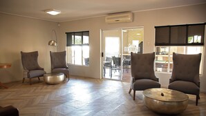 A spacious living area with a herringbone floor, two large armchairs, a round coffee table, and a pendant light. - Stay (Tsantsabane)