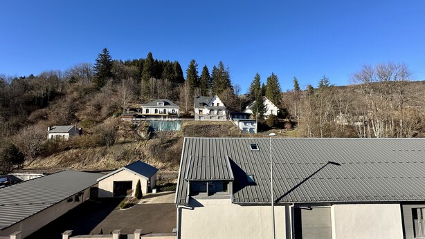 A residential area with multiple houses on a hillside, featuring a mix of architectural styles and a clear sky.