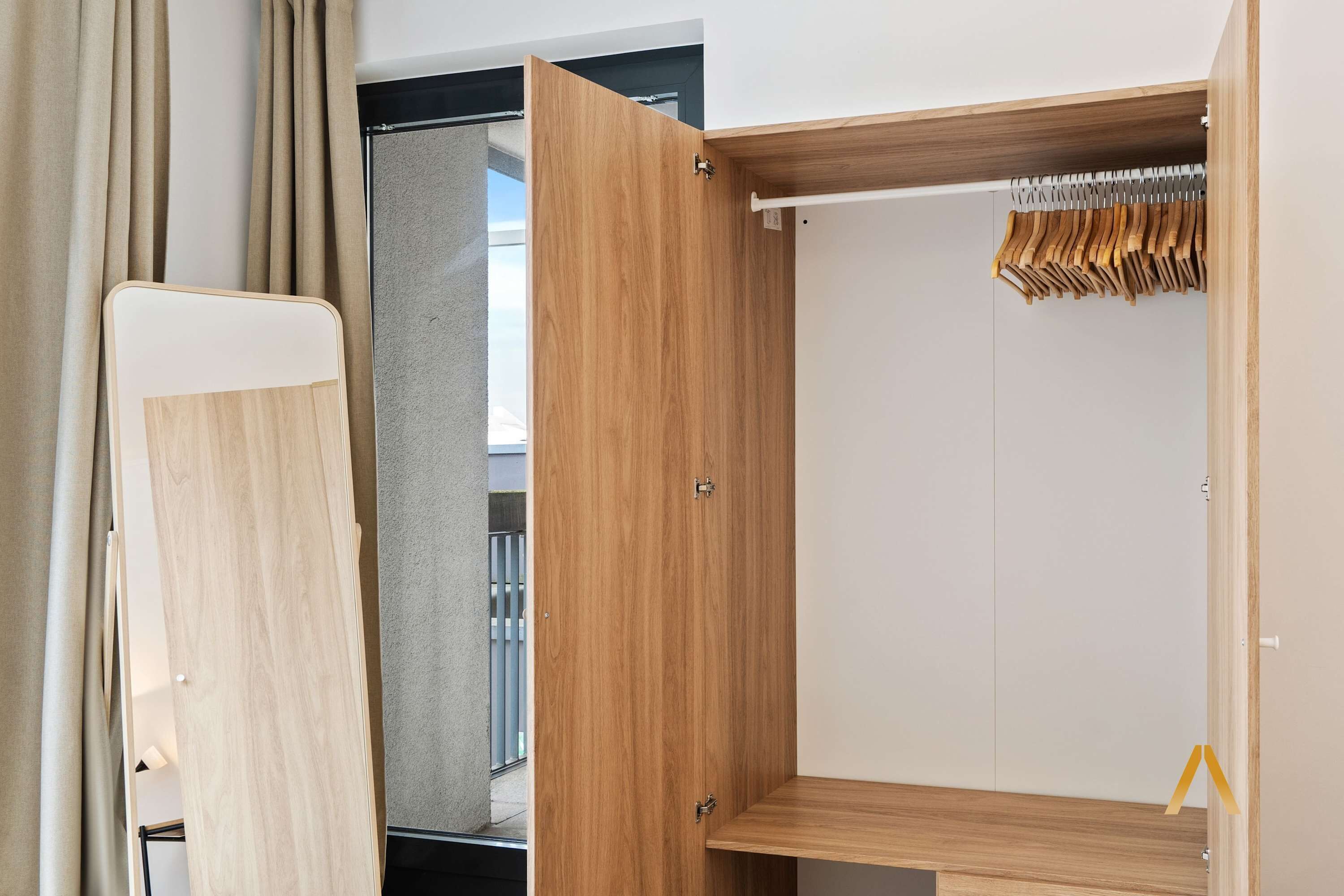 Un armario moderno y abierto con puertas de madera y una barra para colgar.