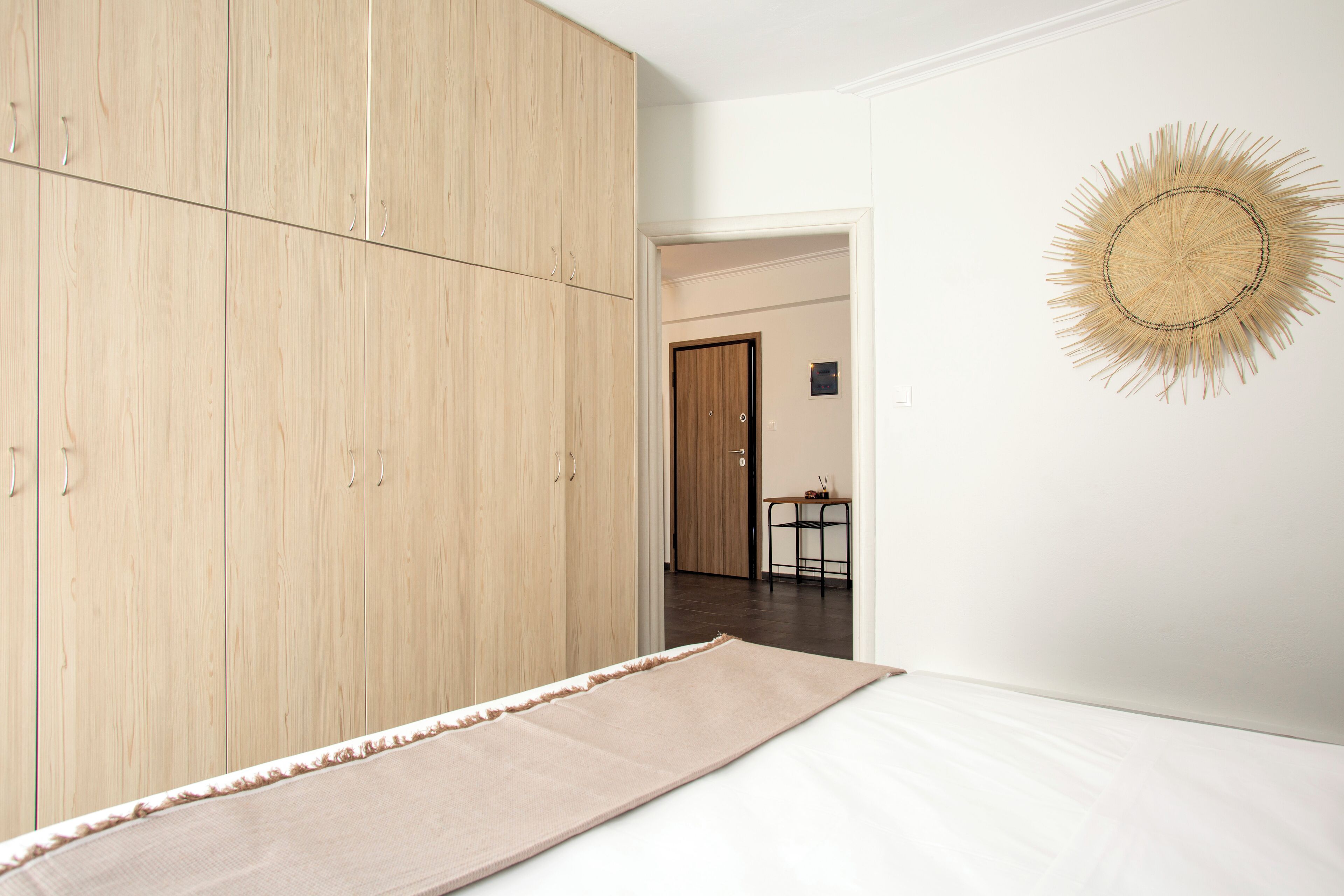 Quarto com guarda-roupa espaçoso, cama, painel decorativo e vista para outro espaço.