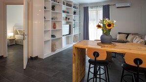 Una sala de estar moderna con una mesa de comedor de madera, sillas negras, una estantería y un sofá.