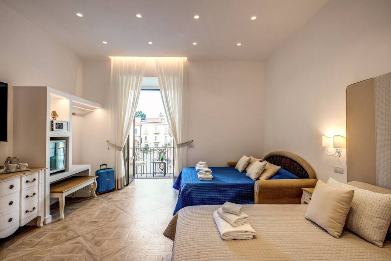 Habitación de hotel con dos camas, un escritorio, una silla y vistas al exterior.