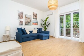 A living room with a blue sectional sofa, a white lamp, and framed pictures on the wall.