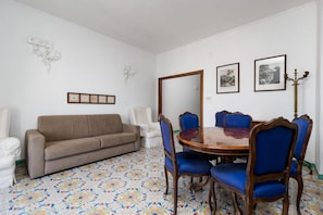 A dining area with a round table, blue upholstered chairs, a beige sofa, and a patterned floor. - Casa Sofia | 3 Bedrooms, 3 Bathrooms & Sea View (Sorrento)