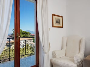 A room with a view of a balcony, a chair, and a framed picture on the wall.