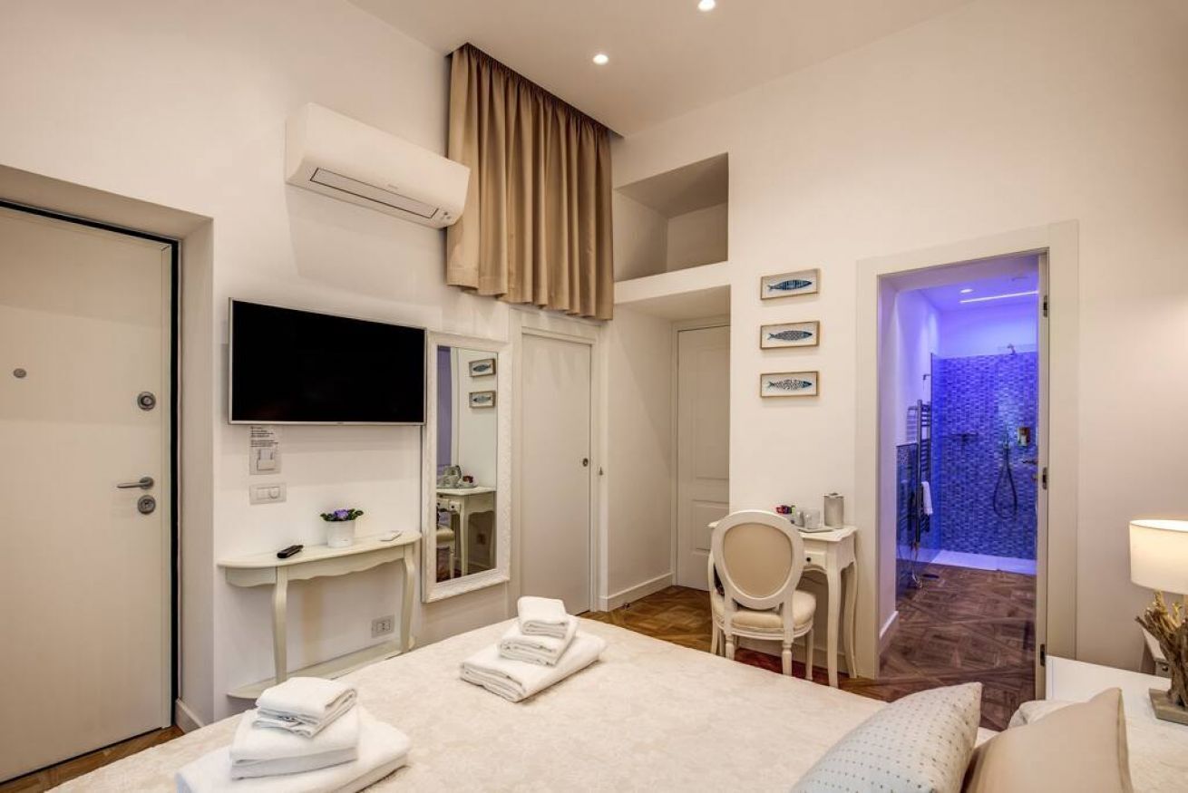 A hotel room with a bed, a desk, a TV, a bathroom, and a shower area.