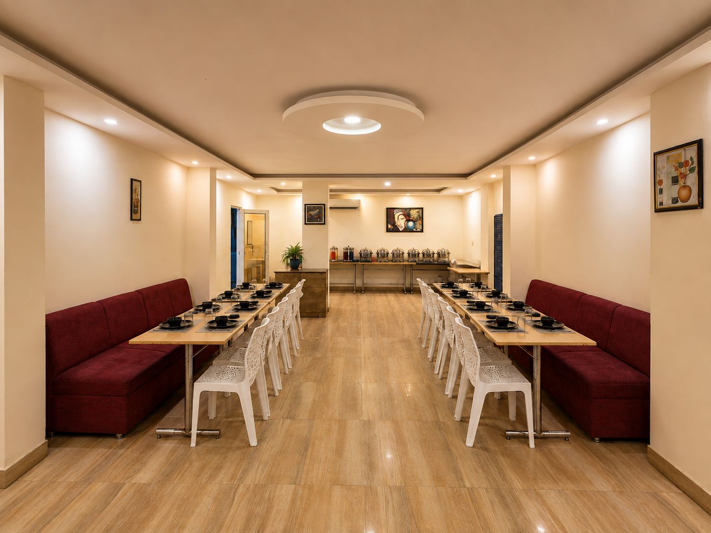 Un salón de conferencias con una larga mesa, sillas blancas, sofás rojos y una lámpara en el techo.