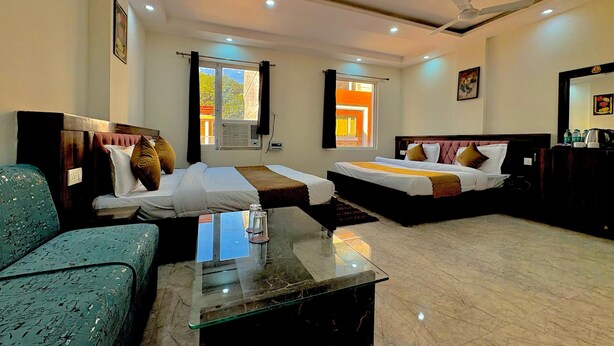 A hotel room with two beds, a glass coffee table, a sofa, and a ceiling fan. - Hotel Royal Central Haridwar (Haridwar)
