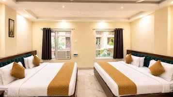 A hotel room with two beds, a ceiling fan, and a window with curtains.