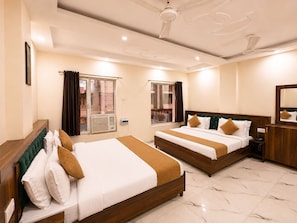 A hotel room with two beds, a wooden headboard, a nightstand, a mirror, and a window with curtains. - Hotel Royal Central Haridwar (Haridwar)