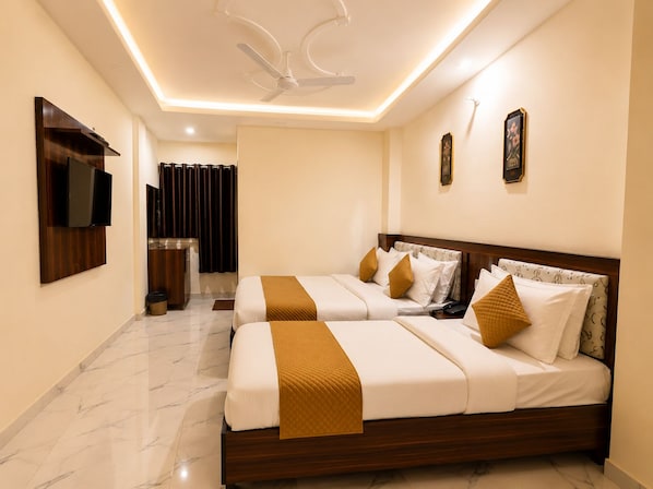 A hotel room with a double bed, a television mounted on the wall, and a ceiling fan.