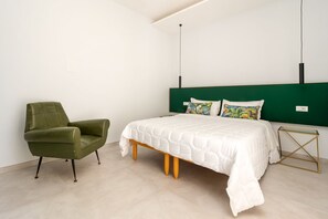 A bedroom with a bed, a green armchair, and a bedside table. - Surya | Elegant Apartment with Balcony in the Heart of Sorrento (Sorrento)
