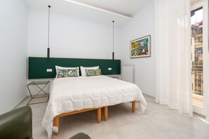 Ein modernes Schlafzimmer mit einem großen Bett, einer grünen Kopfteil, einem Heizkörper und einem Fenster mit Vorhängen.