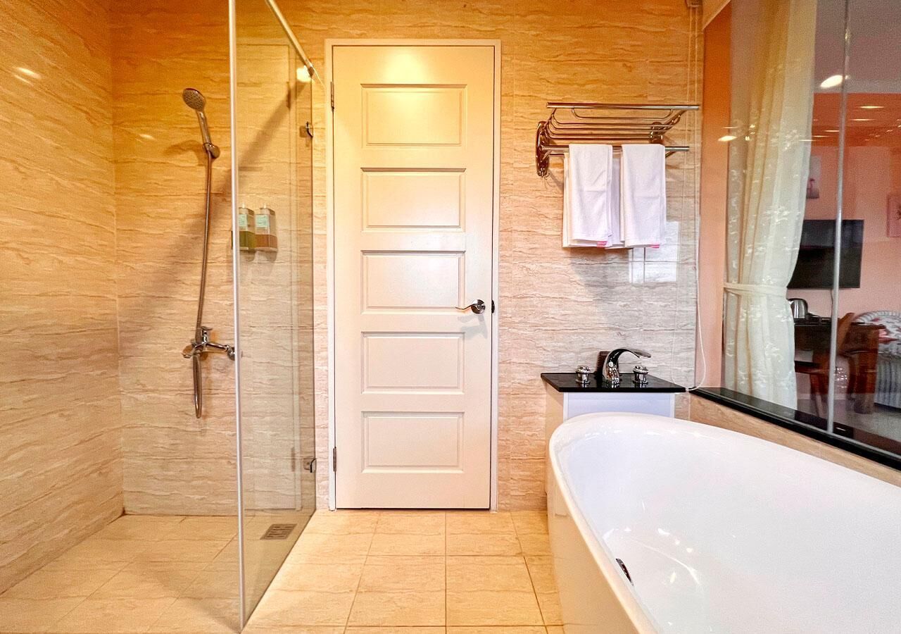 A modern bathroom with a glass-enclosed shower, a white bathtub, and a vanity with a mirror.